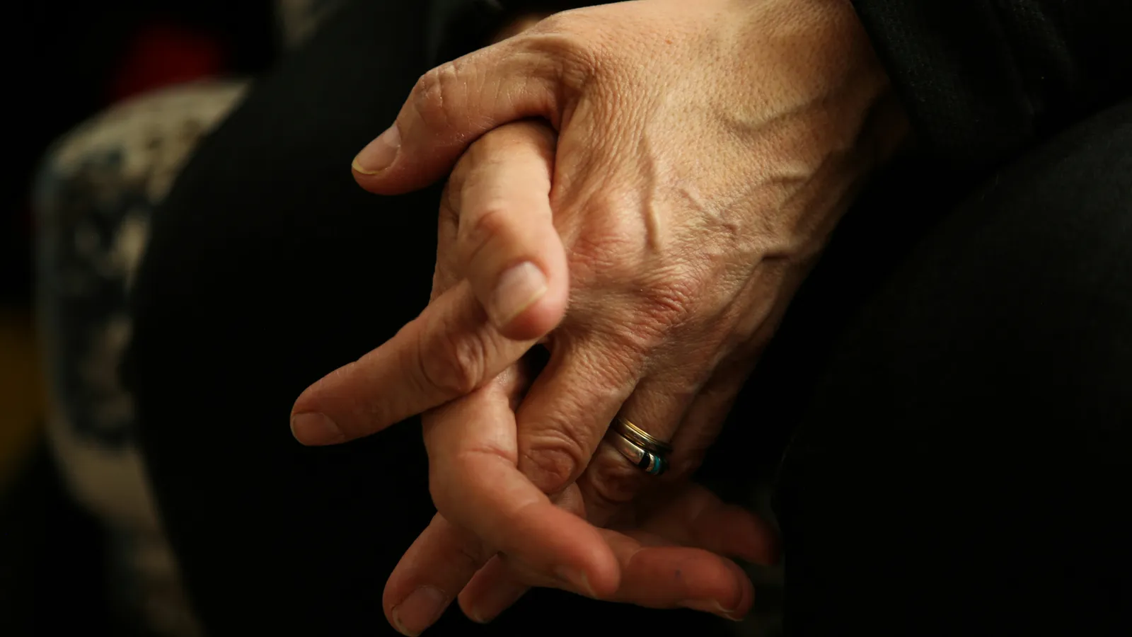 A caregiver's hands gently holding a loved one's hands in support